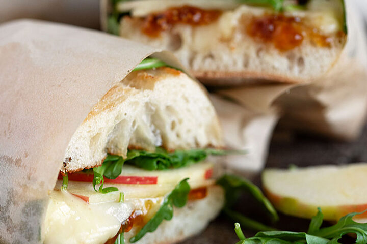 Apple Brie sandwiches wrapped in parchment and sliced.