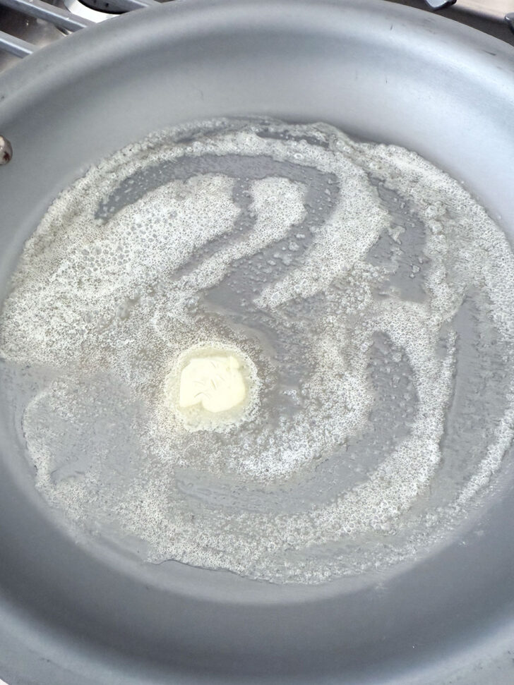 Butter melting in a non-stick skillet.