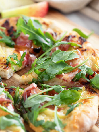 Apple cheddar and pancetta pizza on pizza peel.