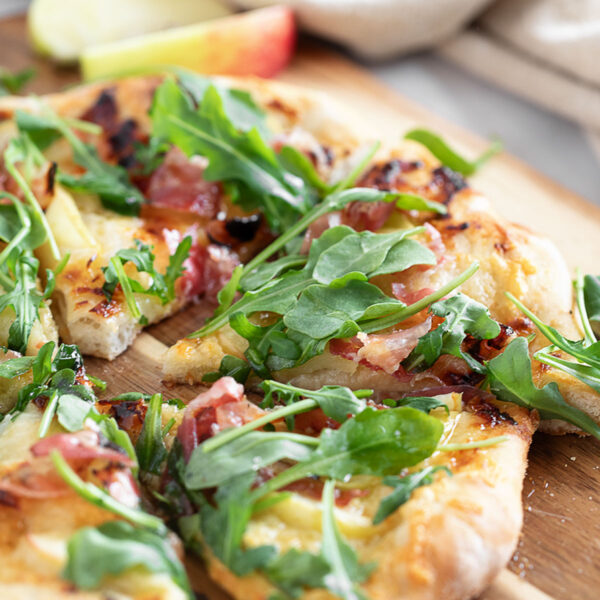 Apple cheddar and pancetta pizza on pizza peel.