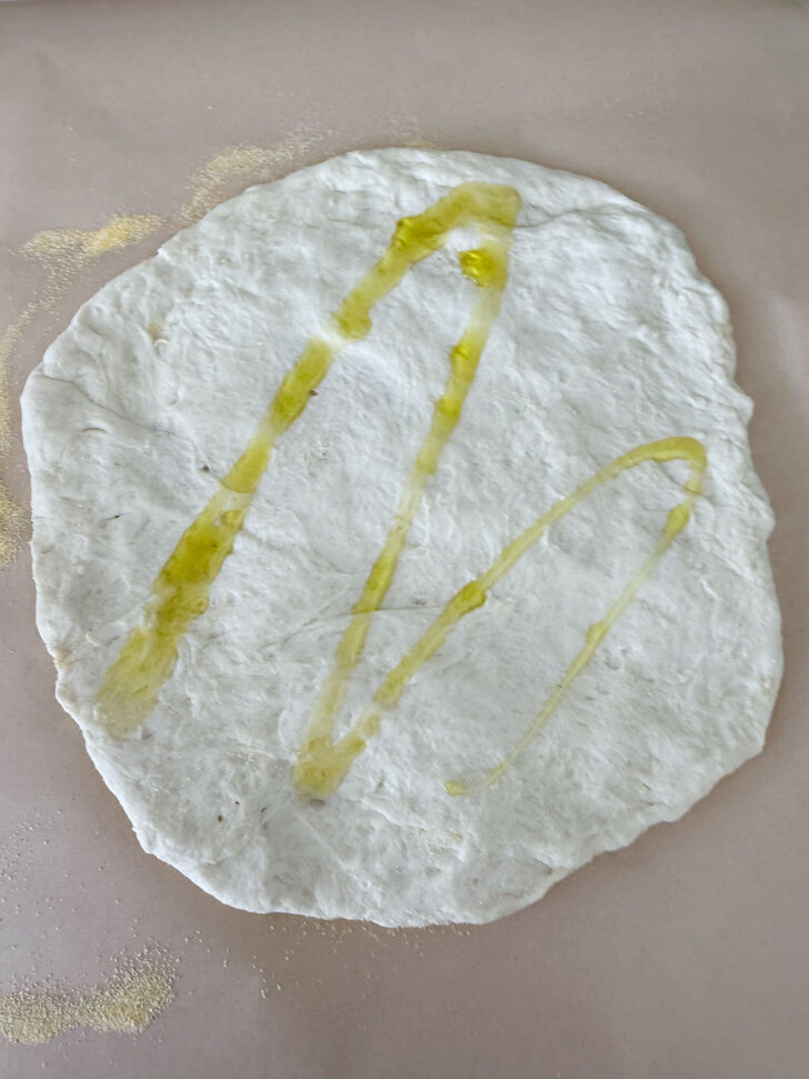 Pizza dough formed into a round and drizzled with olive oil.