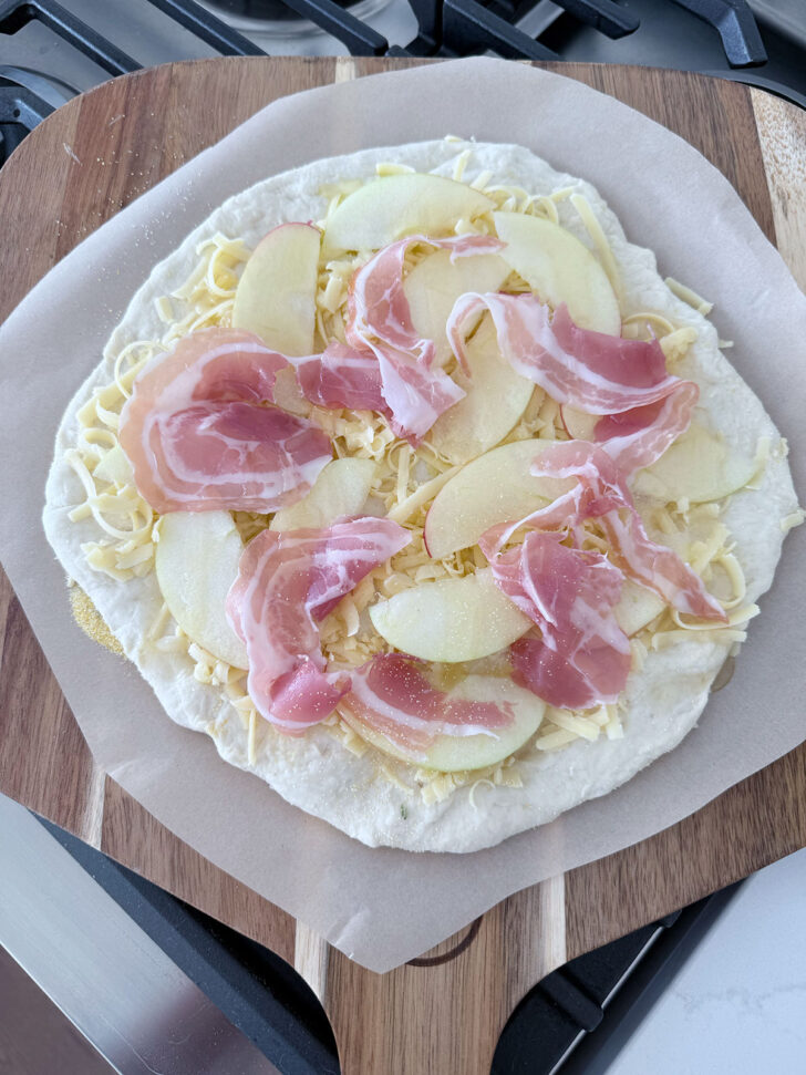 Apple cheddar pizza on pizza peel ready to go into the oven.