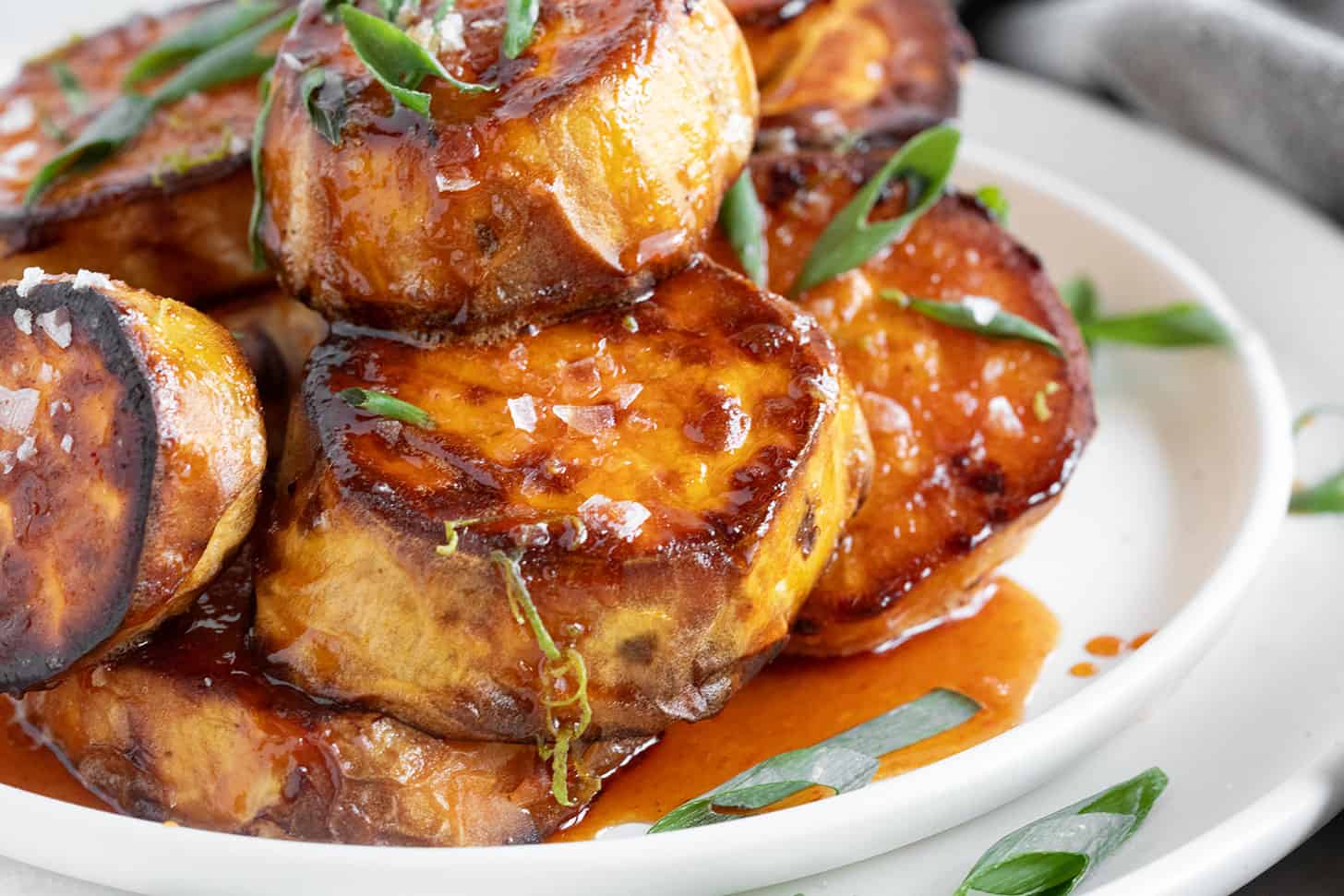 Melt sweet potatoes on a plate with honey sriracha sauce.