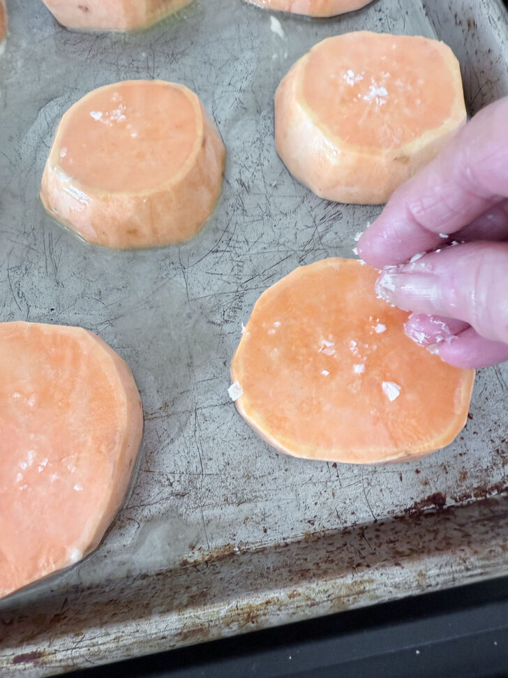 Sprinkling salt on the sweet potato slices.