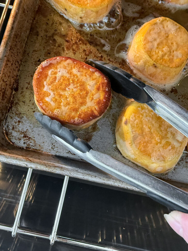 Flipping the sweet potato slices on the baking sheet half way through cooking.