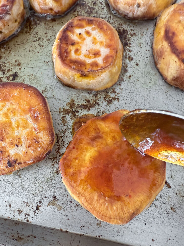Spooning some of the honey sriracha sauce onto the sweet potatoes.