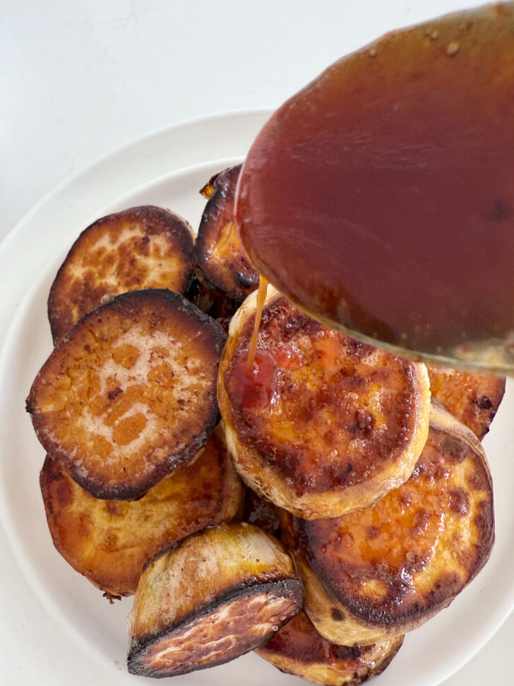 Drizzling more honey sriracha sauce on the finished melting sweet potatoes.