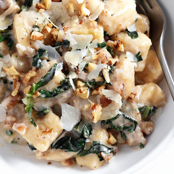 Pear and walnut gnocchi in serving bowl with a fork.