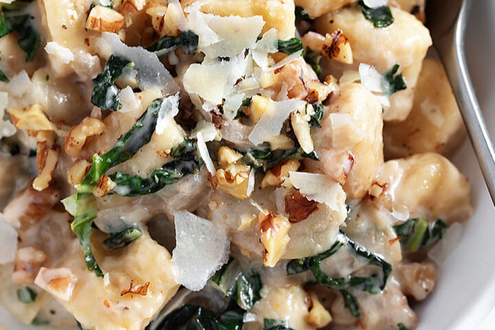 Pear and walnut gnocchi in bowl with fork.