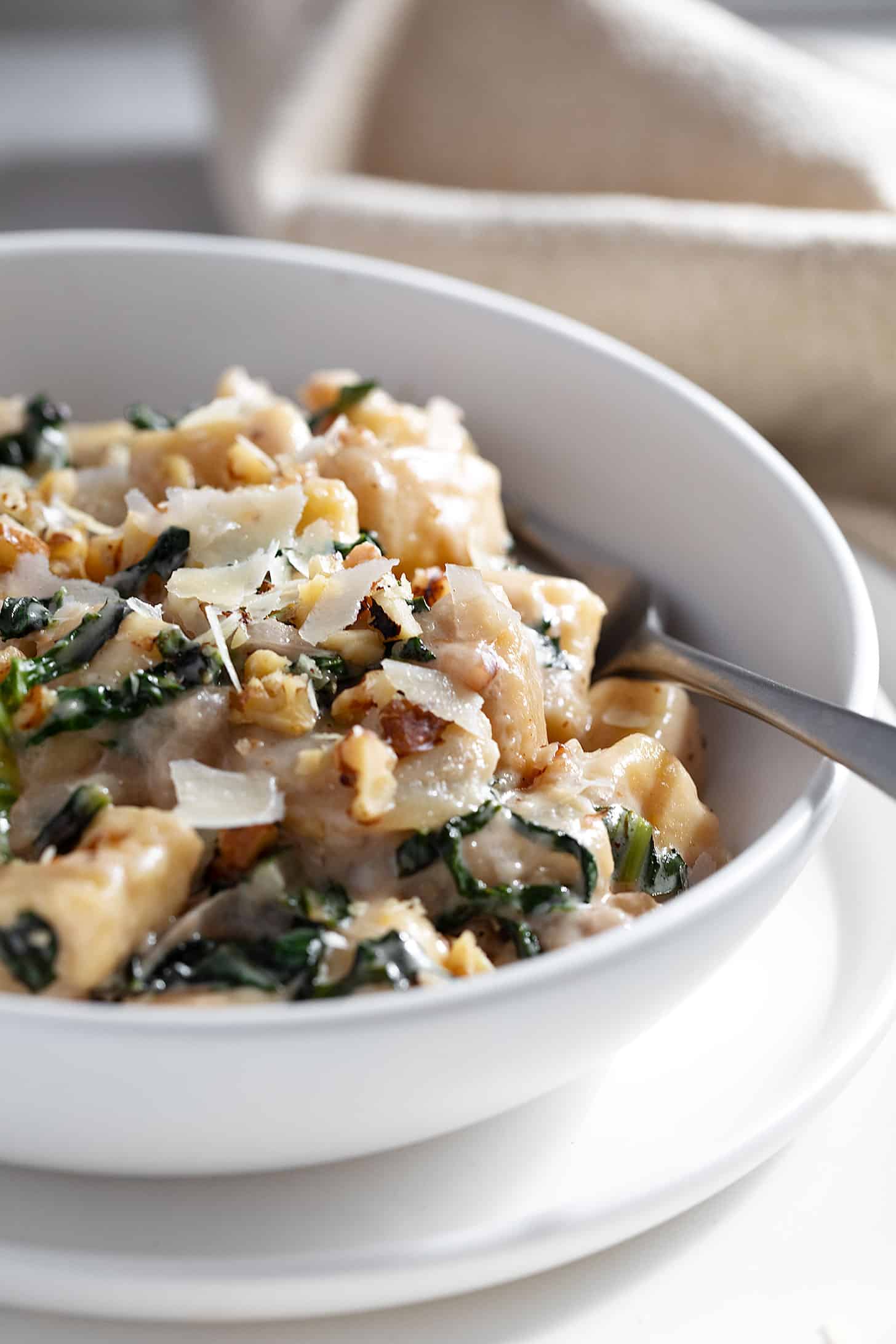 Pear and walnut gnocchi in bowl with fork.