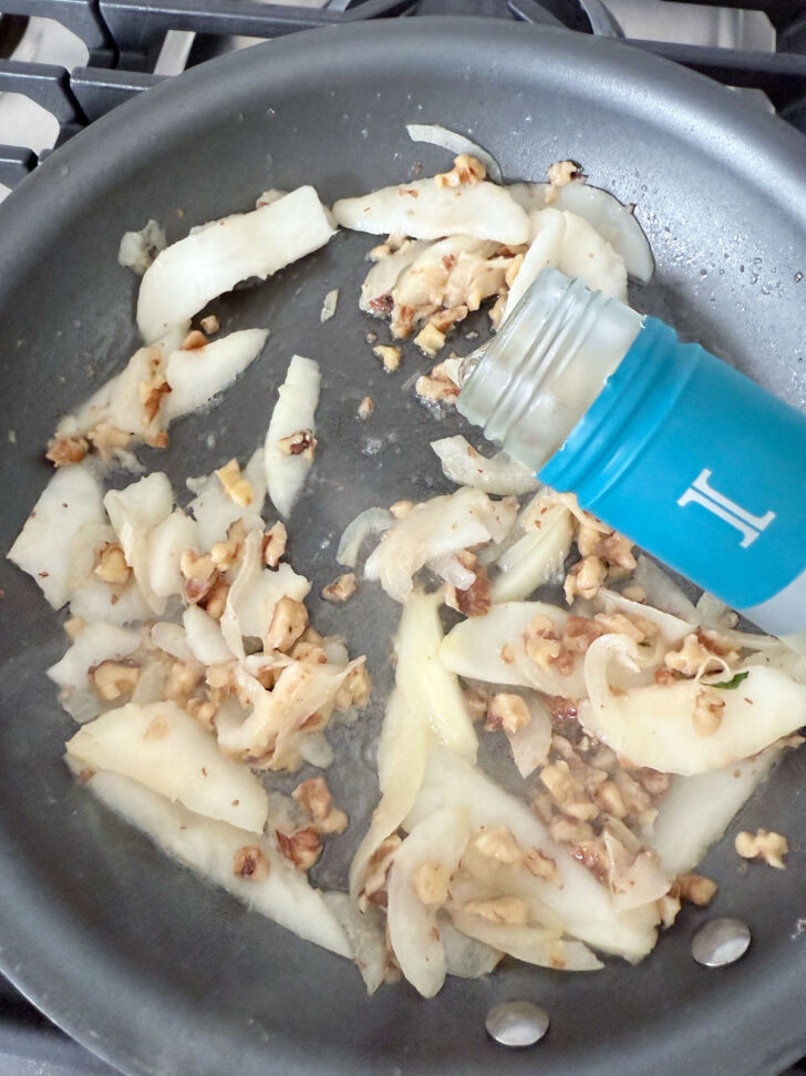 Deglazing the pan with a splash of white wine.
