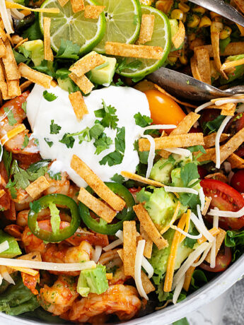 Shrimp taco salad in salad bowl with tongs.