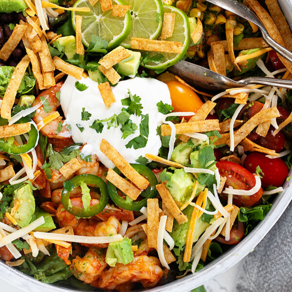 Shrimp taco salad in salad bowl with tongs.