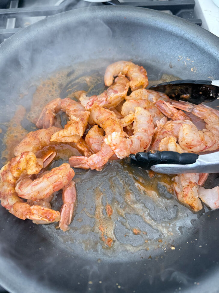 Sautéeing shrimp with taco seasoning in a skillet.