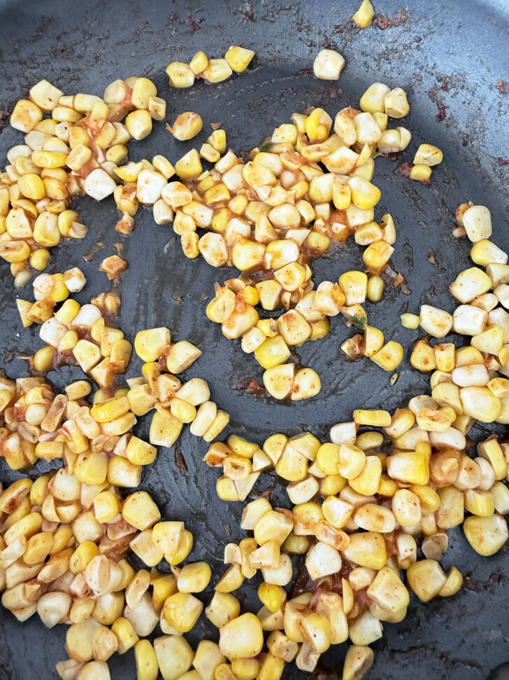 Sautéeing corn with taco seasoning in a skillet.