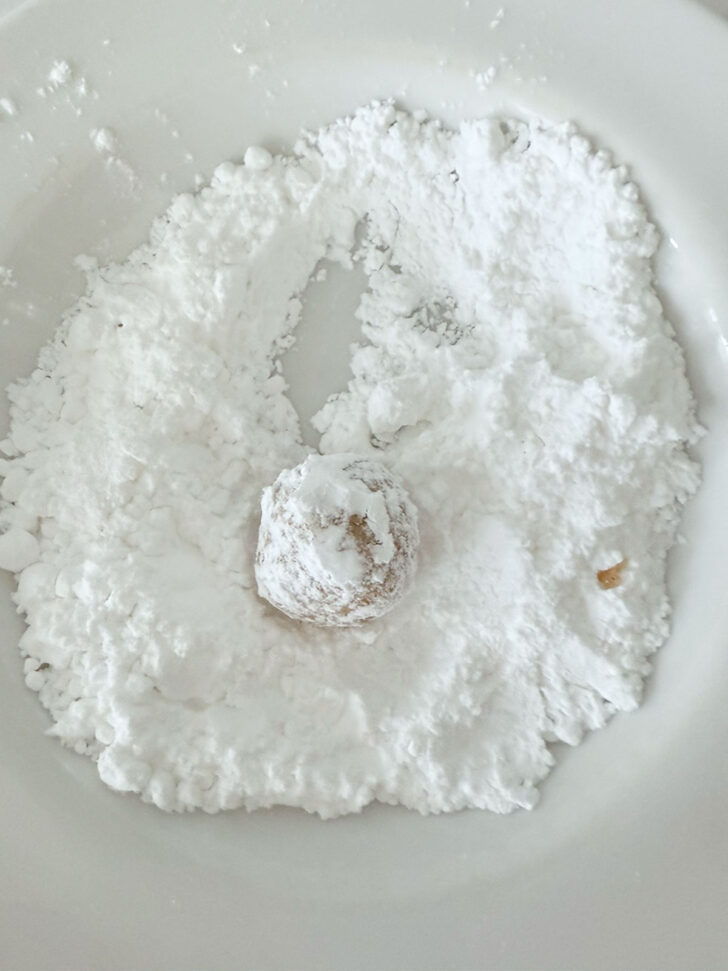 Rolling the cookie dough ball in icing sugar.