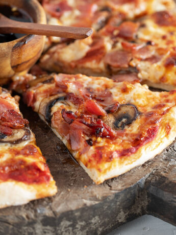 Classic Canadian pizza sliced on serving board.