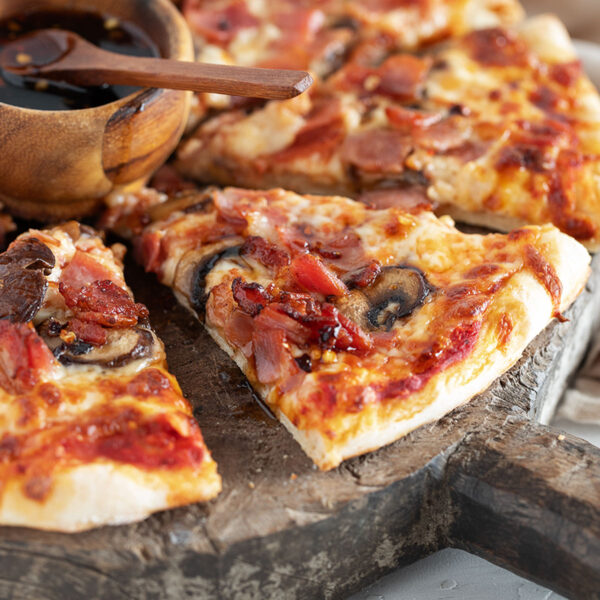 Classic Canadian pizza sliced on serving board.