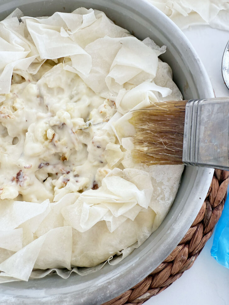 Brushing the phyllo with melted butter.