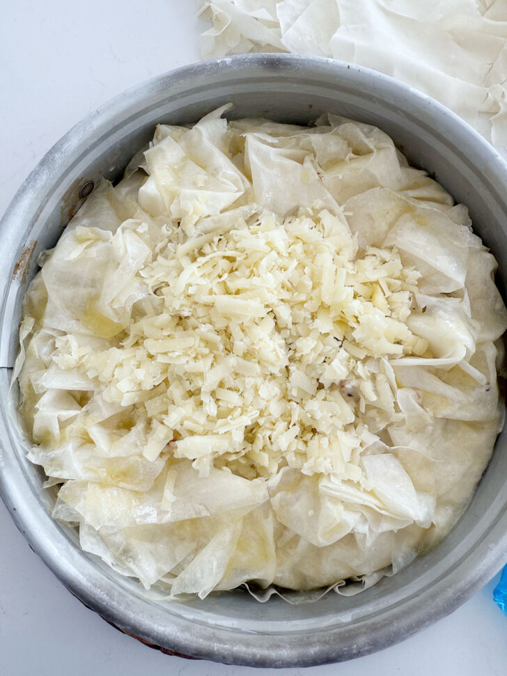 Remaining cheese added to the top of the pie before baking.