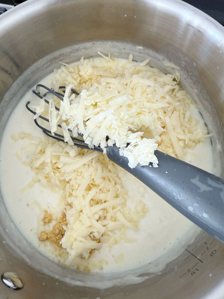 Adding the mustard and shredded cheese to the sauce.