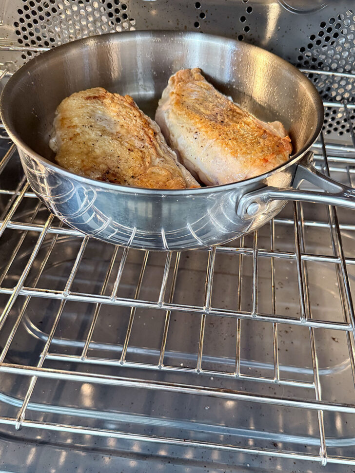 Transferring the chicken to the oven to finish cooking.
