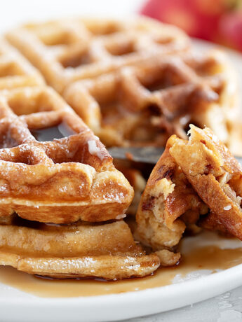 Apple fritter waffles on a plate with a fork.