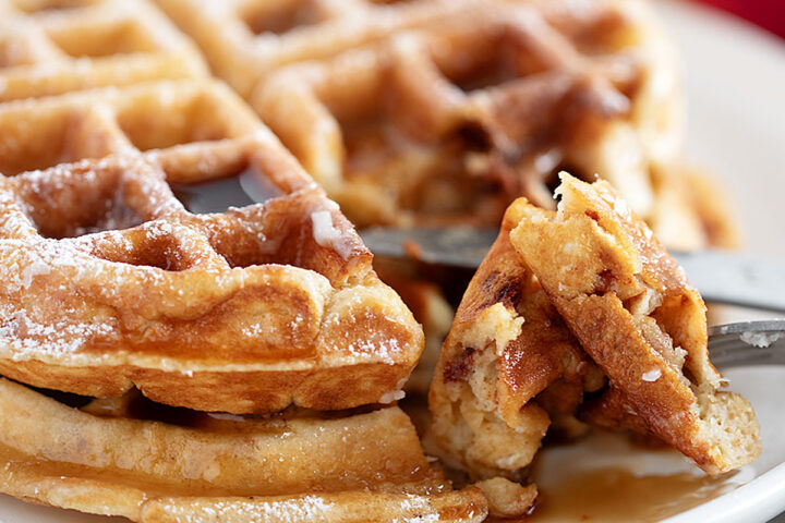 Apple fritter waffles on a plate with a fork.