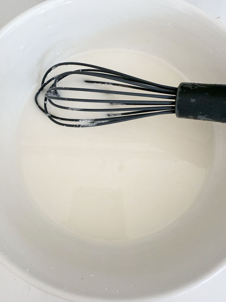Finished glaze in a bowl with a whisk.