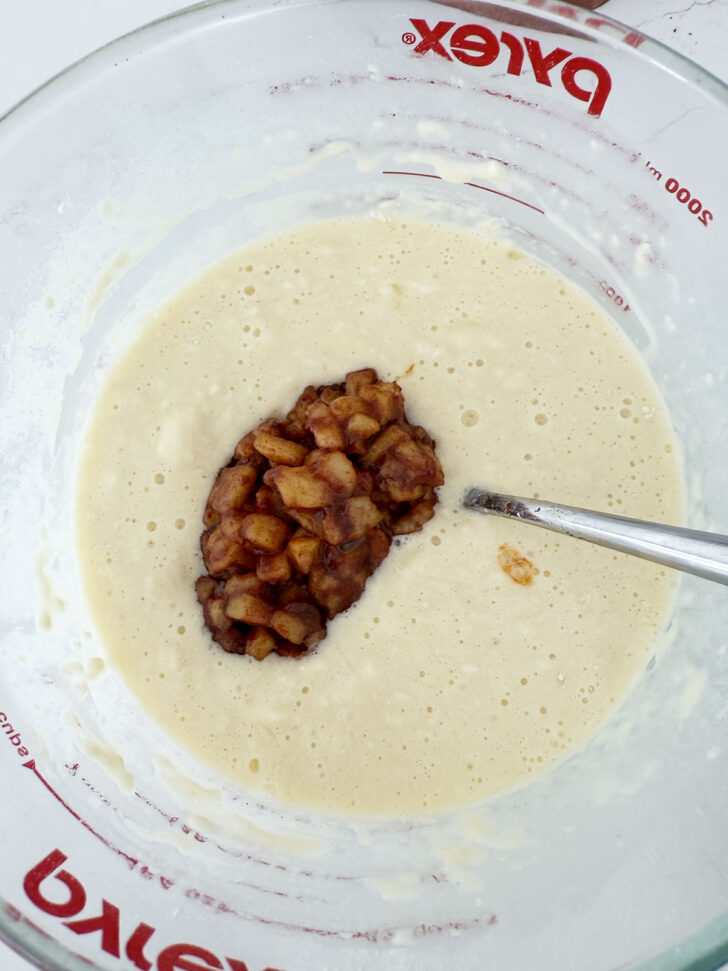 Adding the cooked apples to the waffle batter.