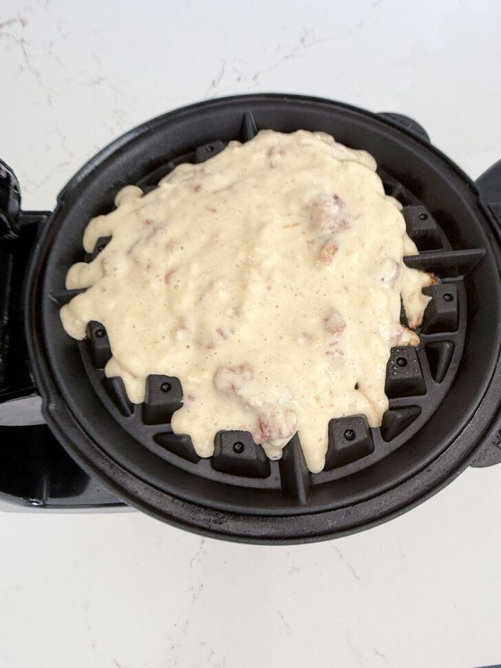 Apple fritter waffle batter is added to the waffle iron.