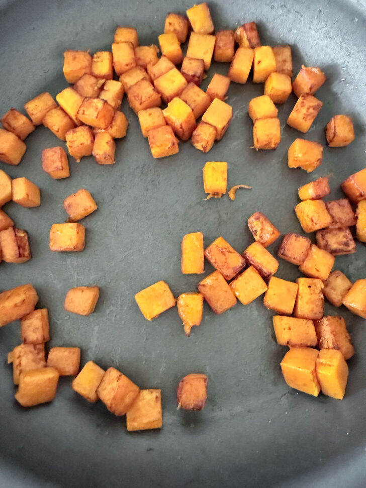 Diced butternuts squash cooking in a skillet.