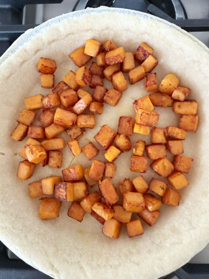 Cooked butternut squash added to the pie shell.