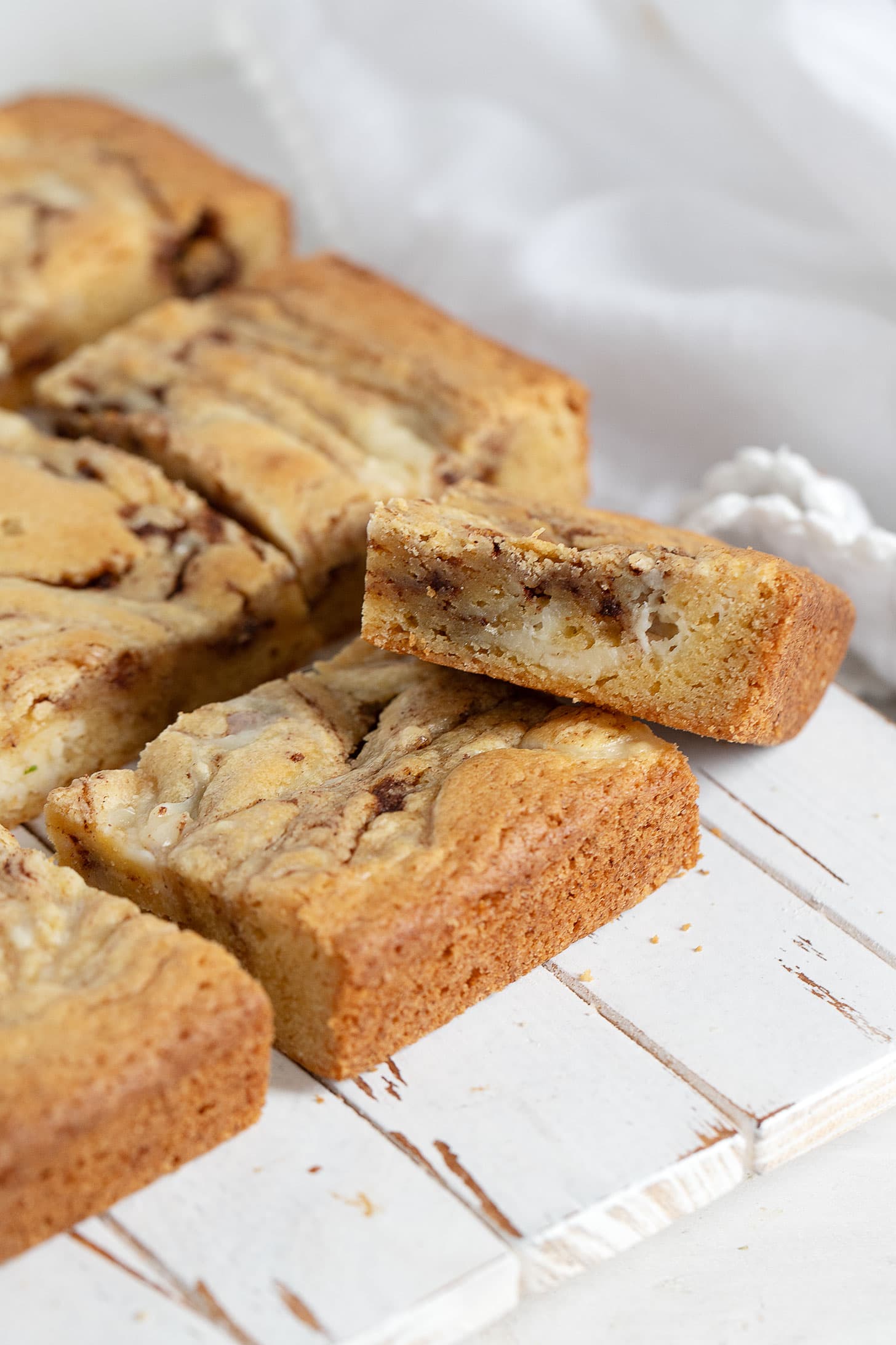 Cinnamon roll blondies cut on a wooden serving board.
