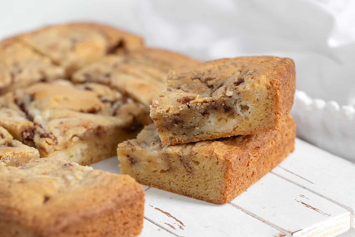 Cinnamon roll blondies cut on a wooden serving board.