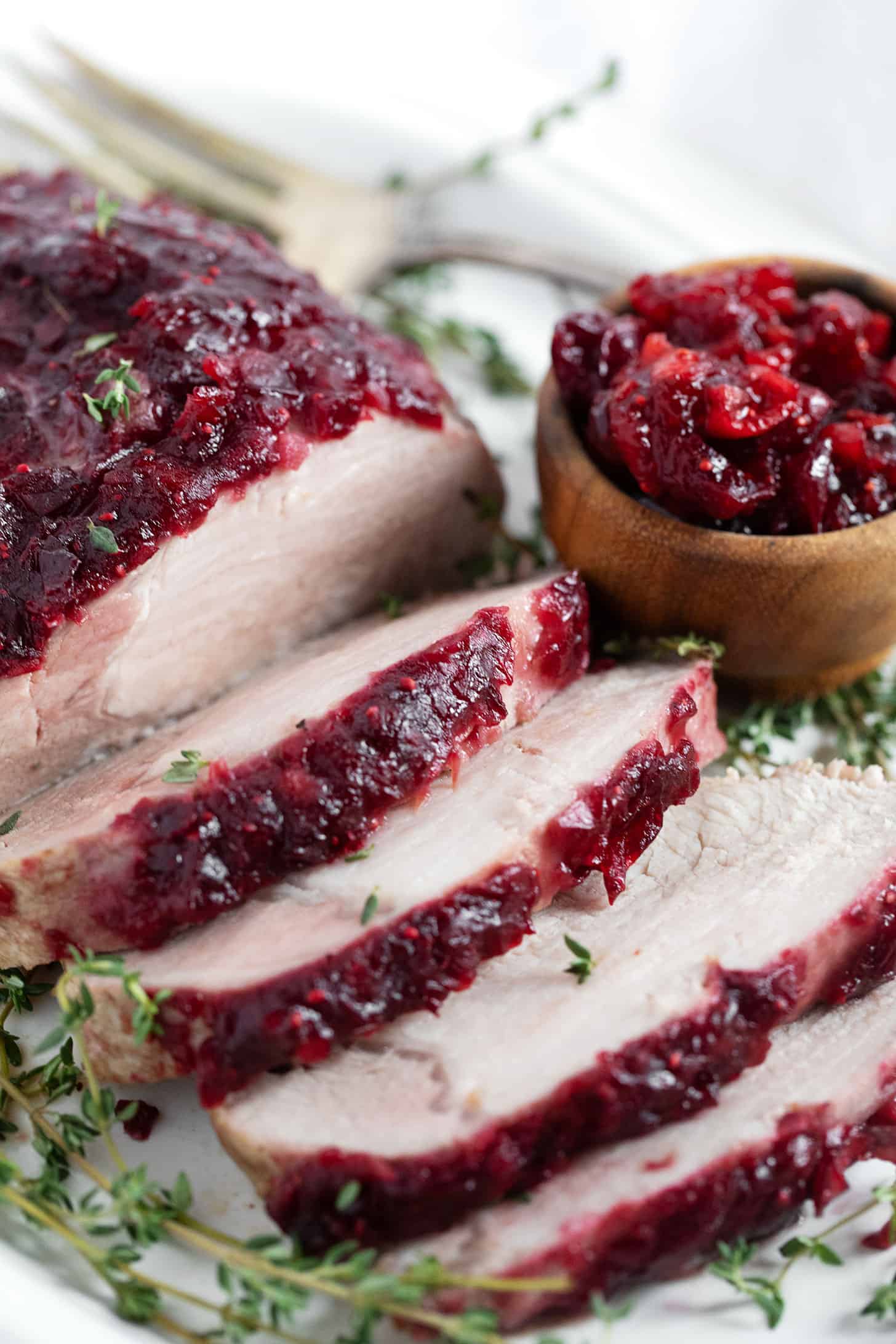 Cranberry apple glazed pork roast sliced on a serving plate.