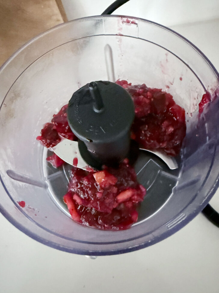 Processing the remaining cranberry apple mixture into a glaze in a food processor.