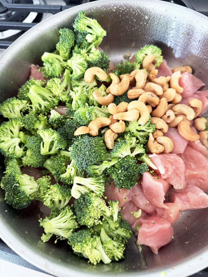 Broccoli, chicken and cashews added to a hot skillet.
