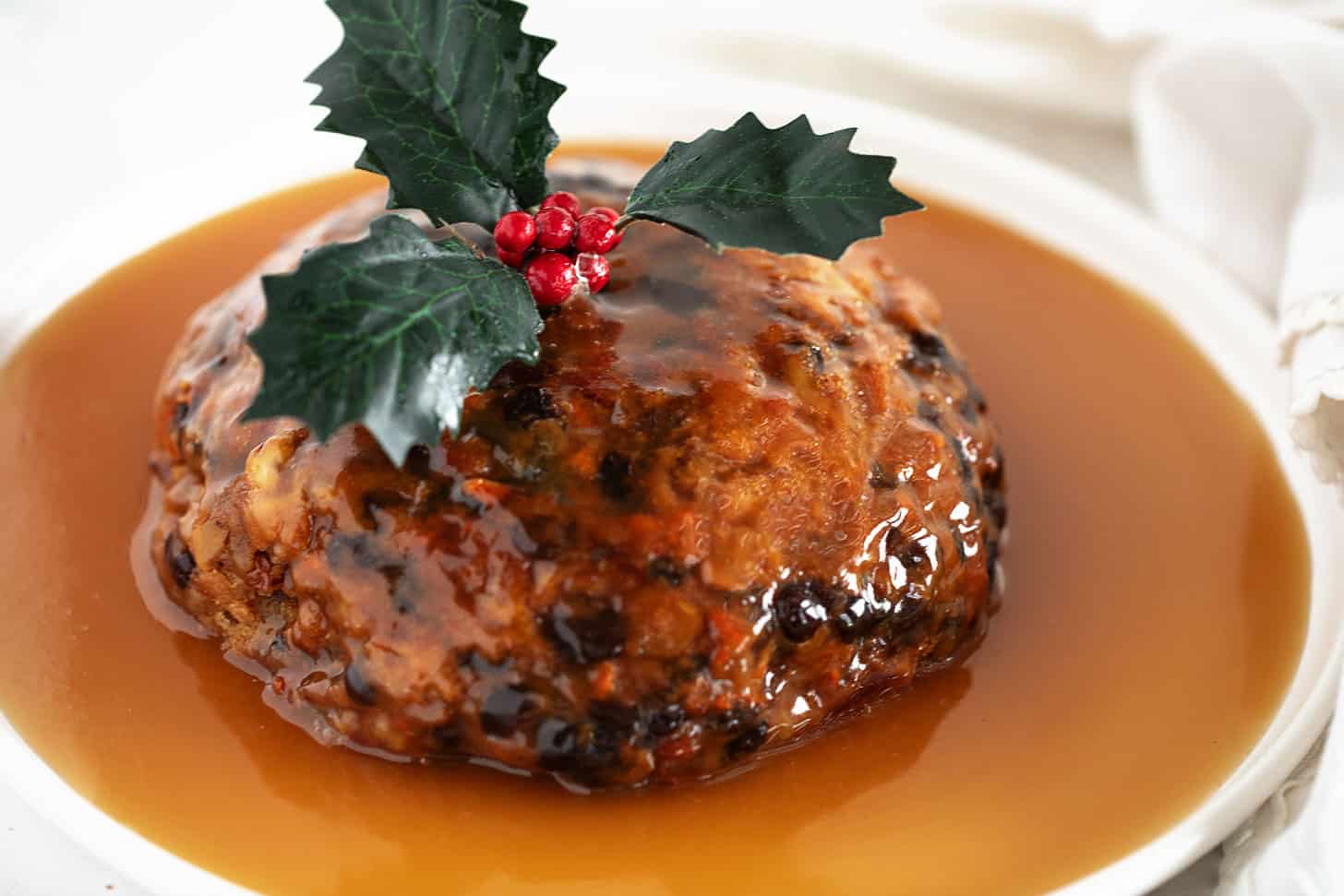 Christmas pudding with rum sauce on a serving plate.