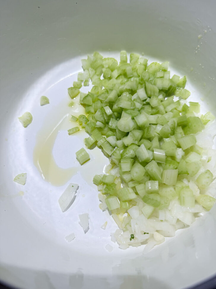 Onion and celery added to a hot soup pot.