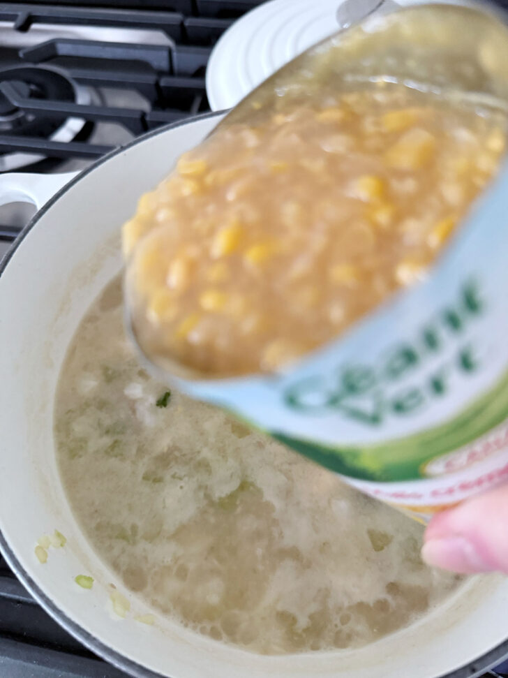 Adding a can of creamed corn to the cod chowder.