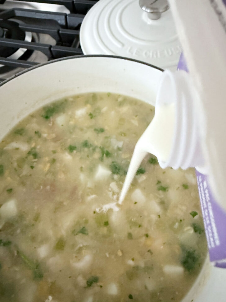 Drizzling a little heavy cream into the chowder.