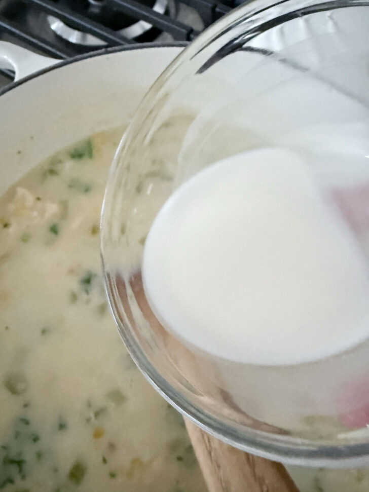 Adding a cornstarch slurry to thicken the chowder.