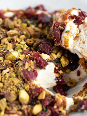 Cranberry balsamic topped whipped ricotta in a bowl with a baguette slice.