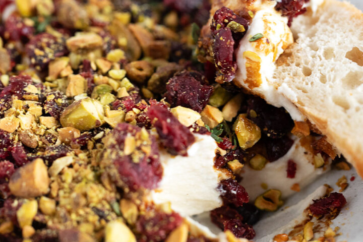 Cranberry balsamic topped whipped ricotta in a bowl with a baguette slice.