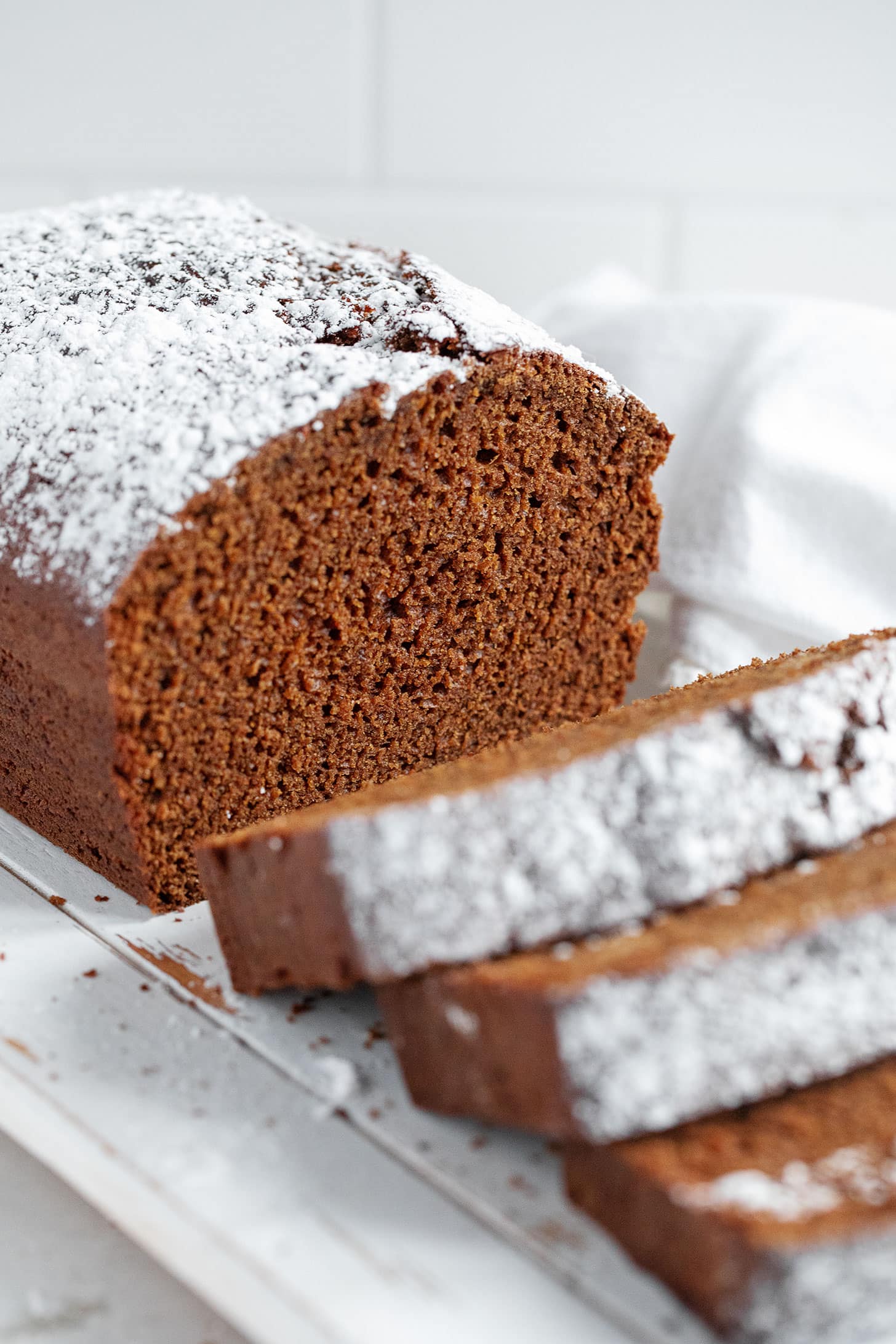 Old-fashioned gingerbread loaf sliced on a cutting board.