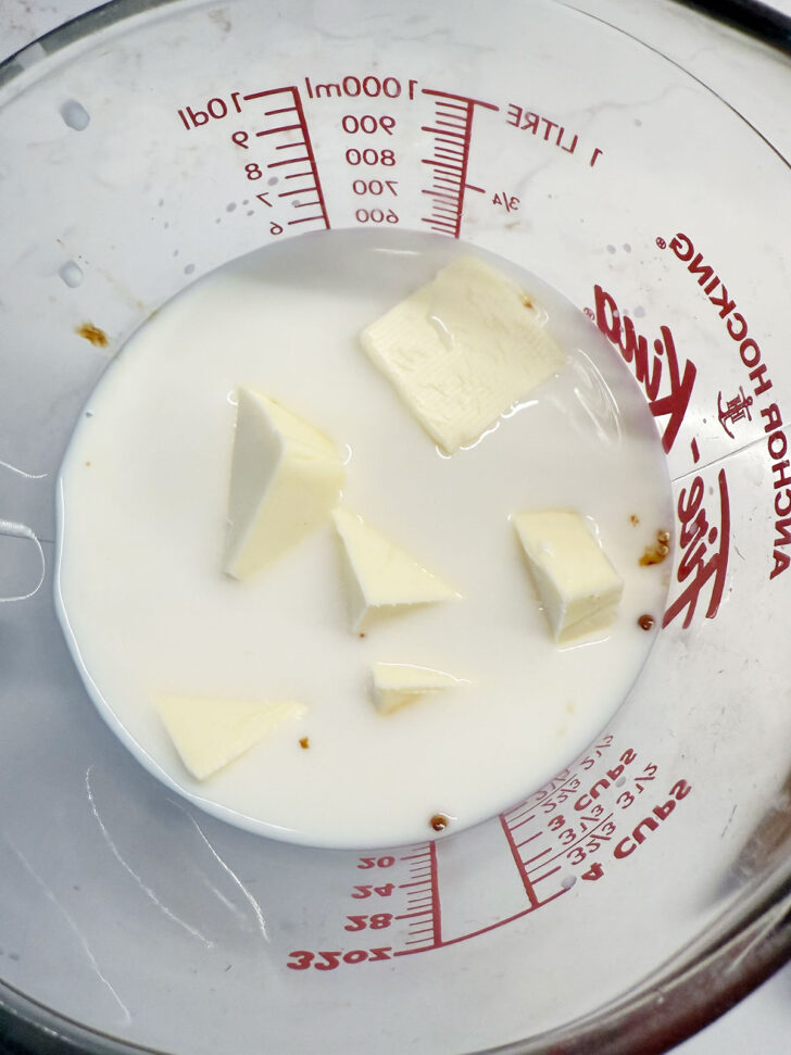 Butter cubes in a measuring cup with milk.
