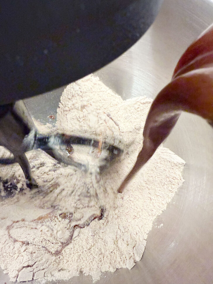 Adding the molasses mixture to the dry ingredients in a stand mixer.