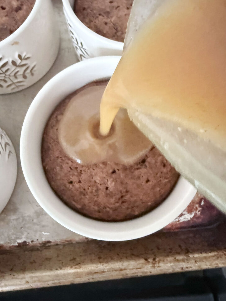 Pouring the toffee sauce over the cooked gingerbread sticky toffee pudding.