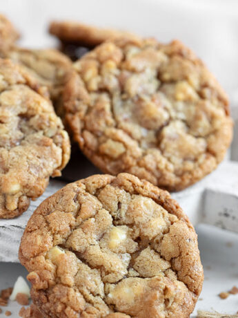 Toffee, walnut and white chocolate cookies on serving board.